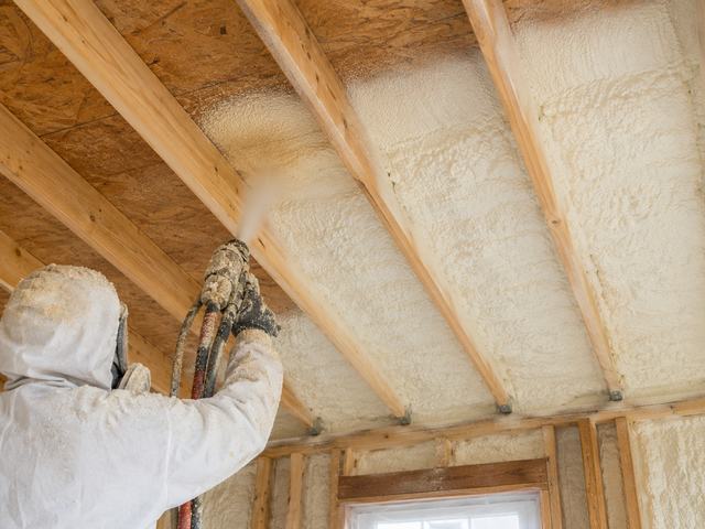 Spray foam insulation being sprayed on the underside of a roof deck