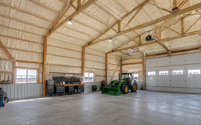 Large farm building with spray foam insulation on the roof and walls and a tractor inside