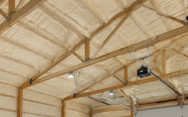 Roof trusses and purlins in a large building with spray foam on the underside of the roof